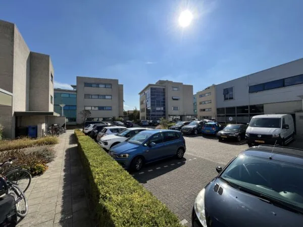 Zonnige parkeerplaats tussen moderne kantoorgebouwen in Leidse Rijn.